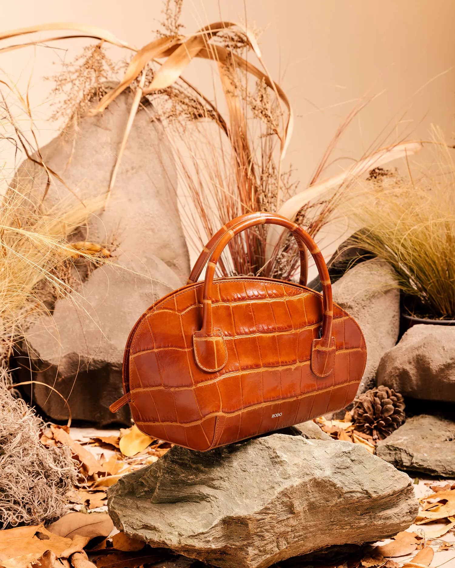 Bauletto in pelle cuoio su una roccia, fra spighe secche e foglie
