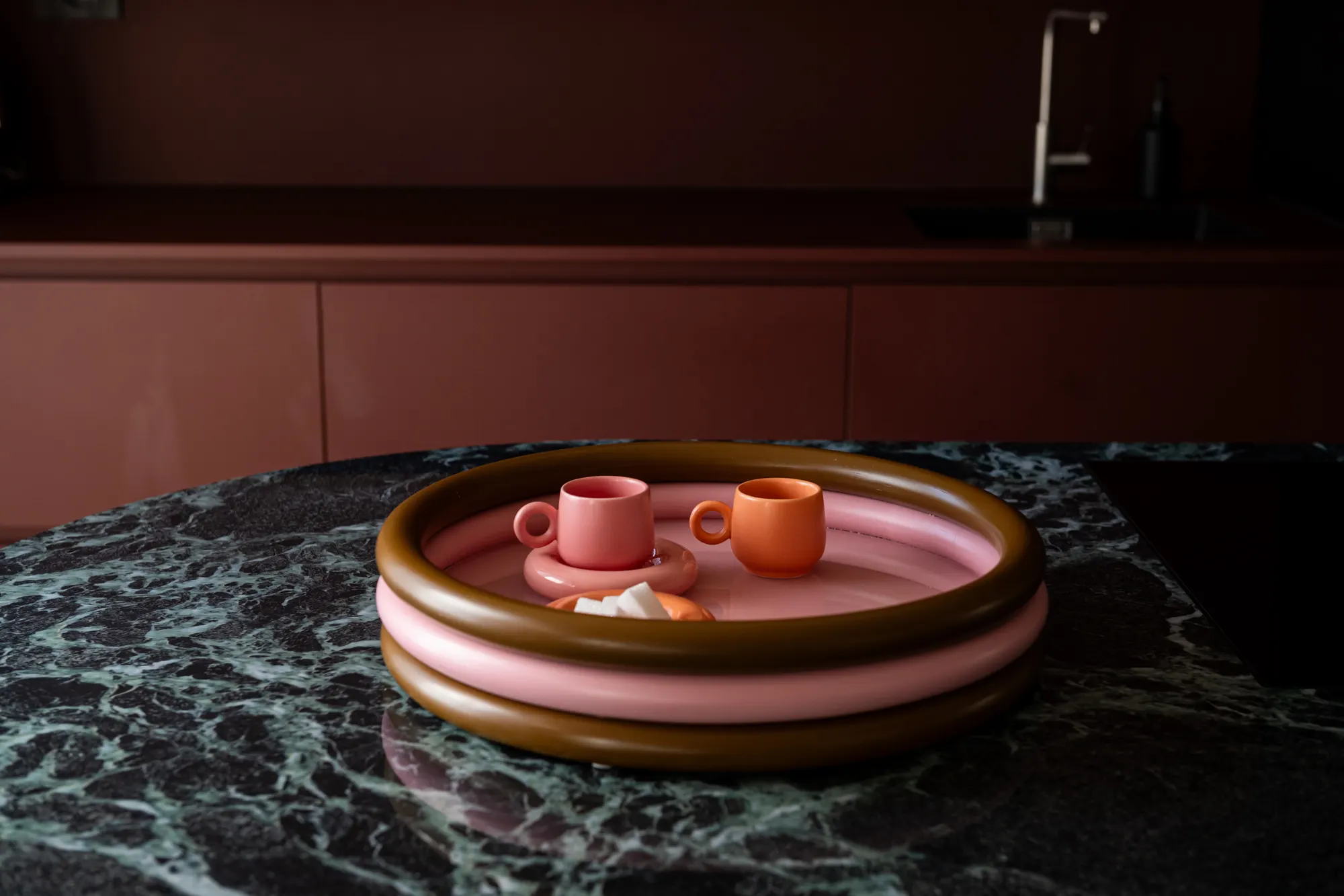 Vassoio rosa e ottone su un piano in marmo verde scuro, cucina bordeaux