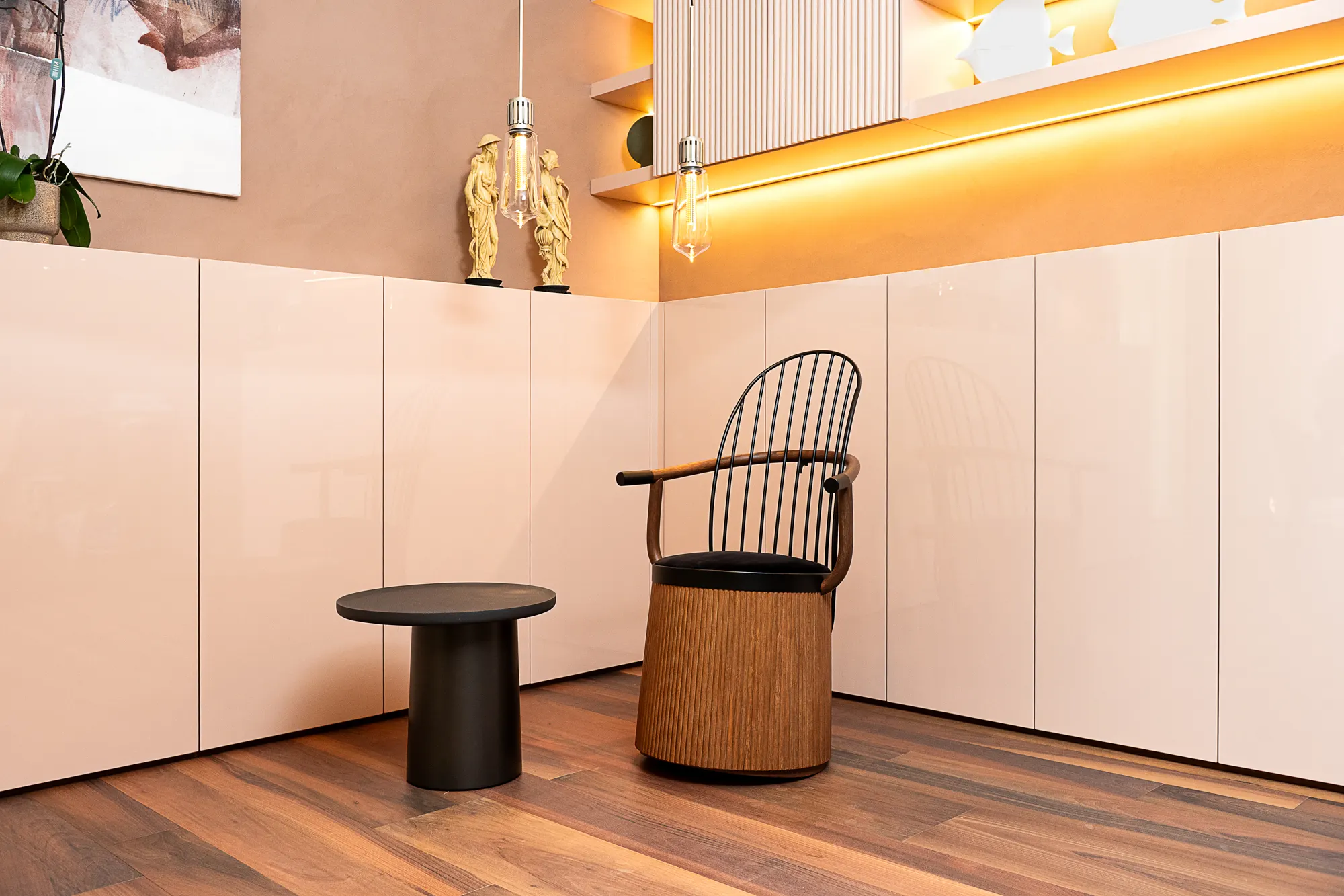 Sedia con seduta intrecciata in una cucina laccata rosa, tavolino nero e parquet