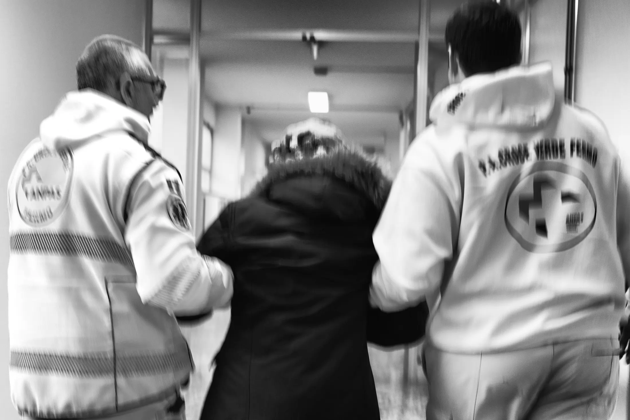 Due volontari accompagnano una persona lungo un corridoio d’ospedale