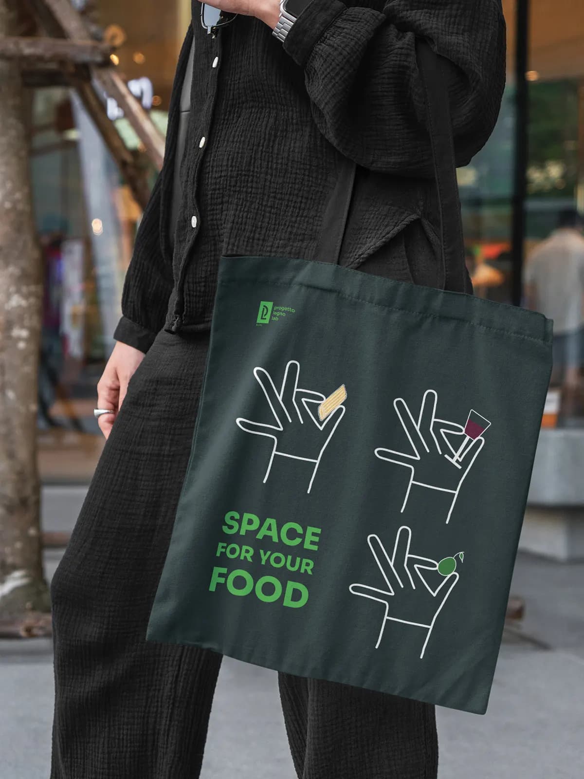 Borsa di tela verde con illustrazione e la scritta Space for your food, indossata