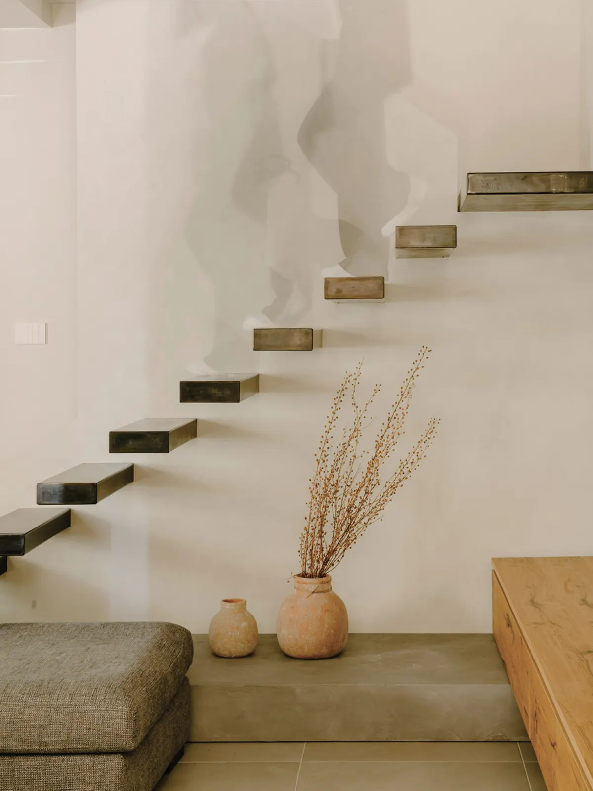 Scala in legno su parete curva con vasi e fiori secchi