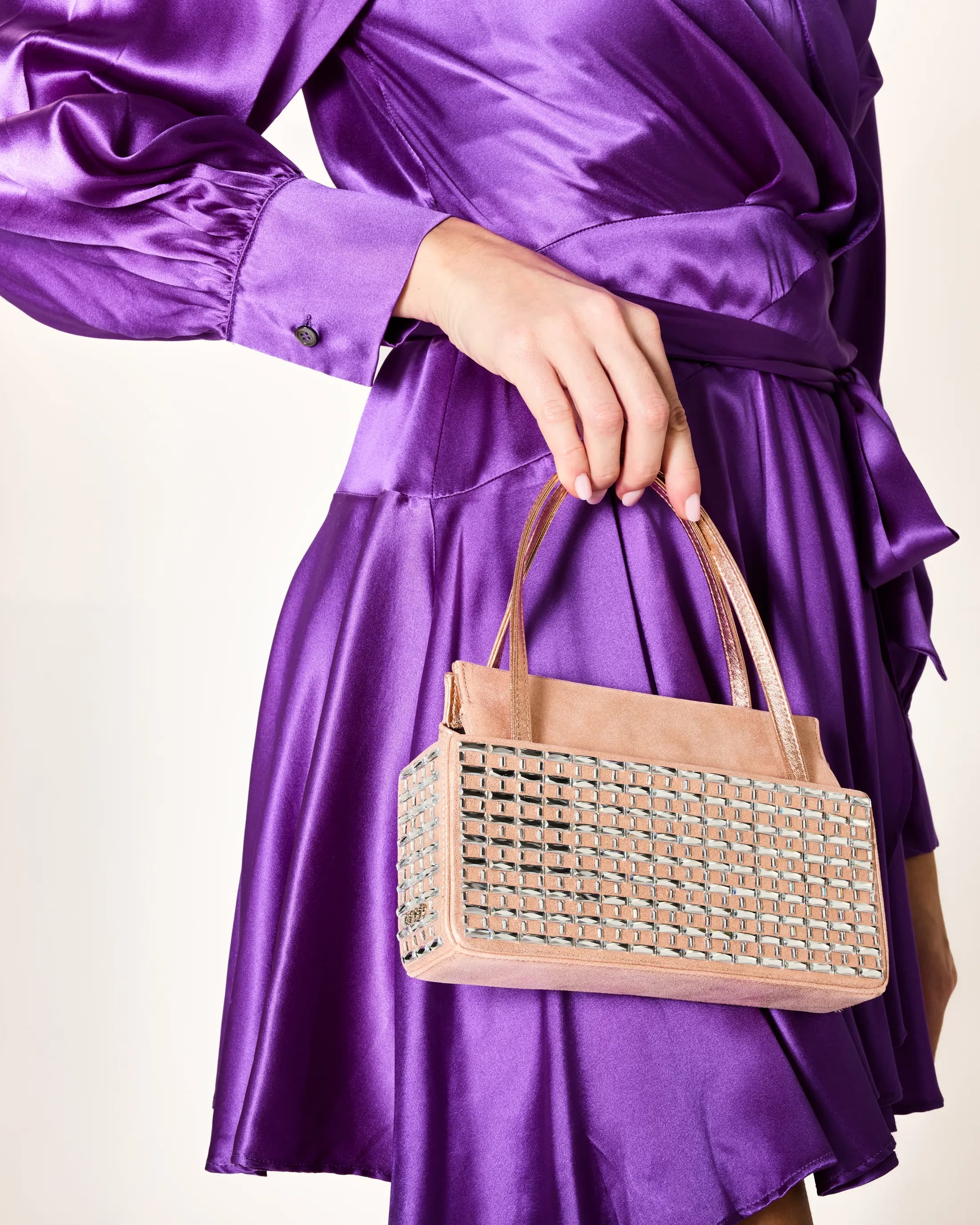 Abito in raso viola con borsa a mano beige borchiata
