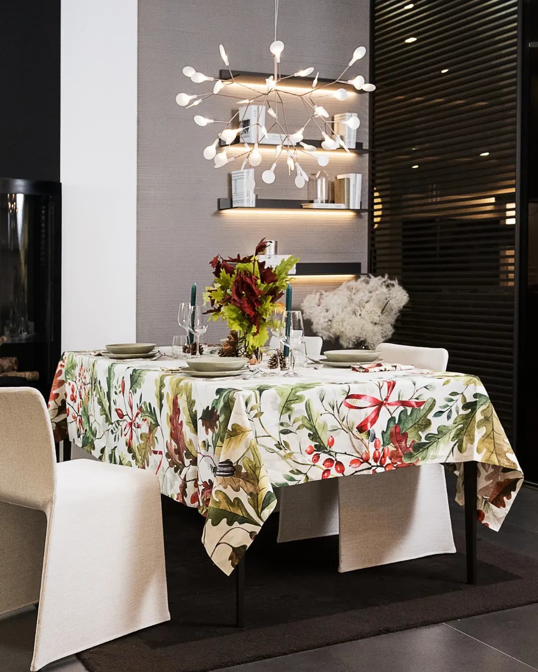 Tavola apparecchiata in uno showroom, tovaglia a stampa botanica e lampadario