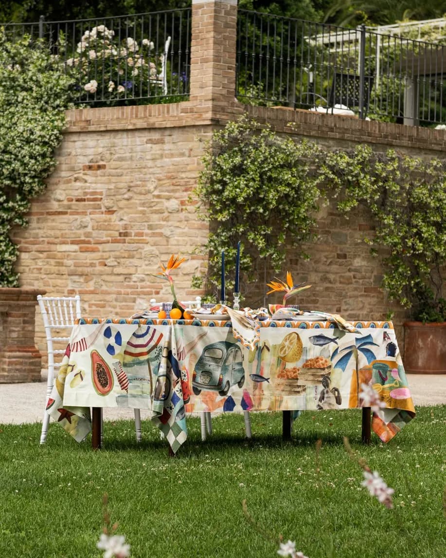Tavola in giardino contro un muro in mattoni, tovaglia a stampa colorata
