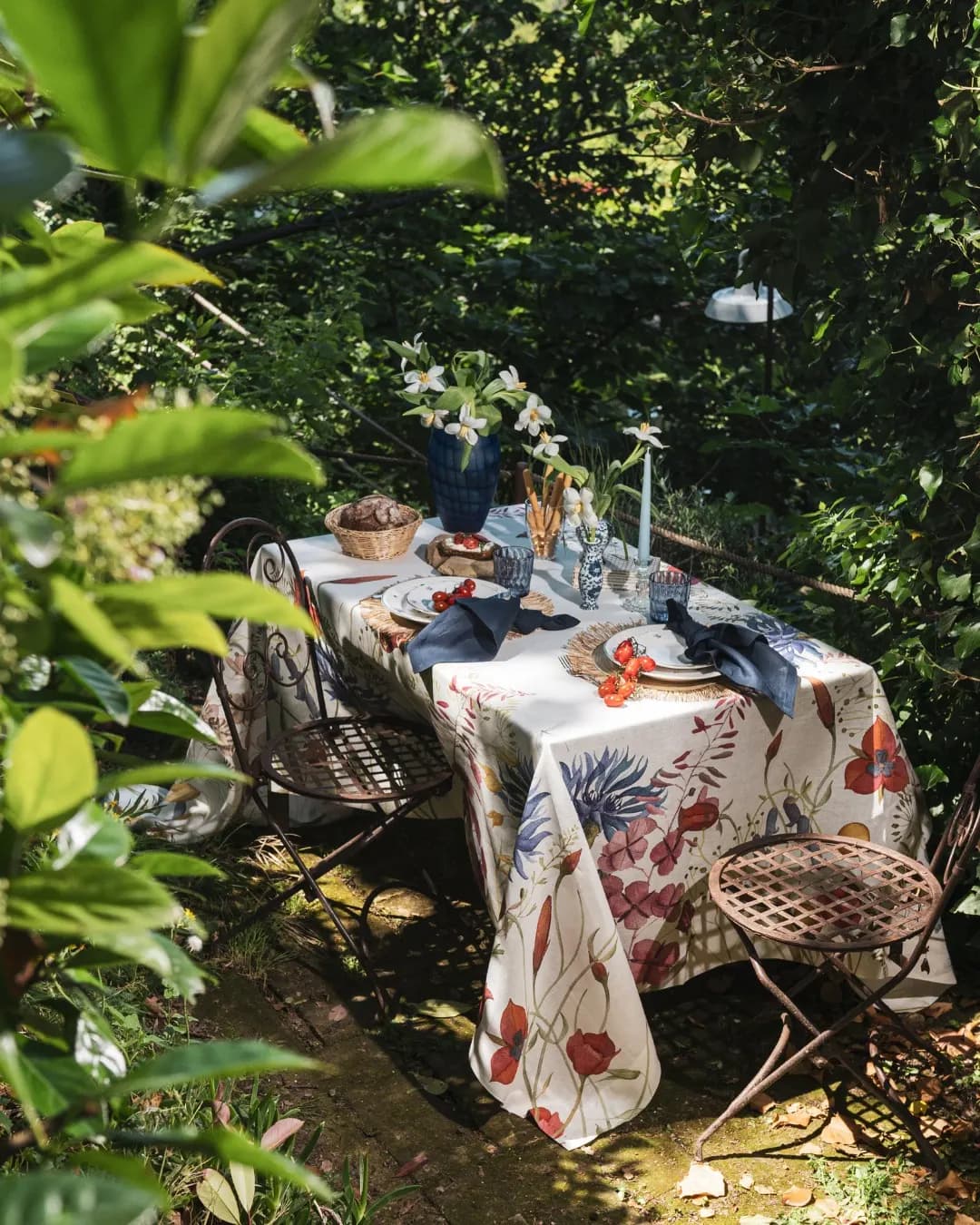Tavola nel verde vista dall’alto, tovaglia a stampa botanica e ceste