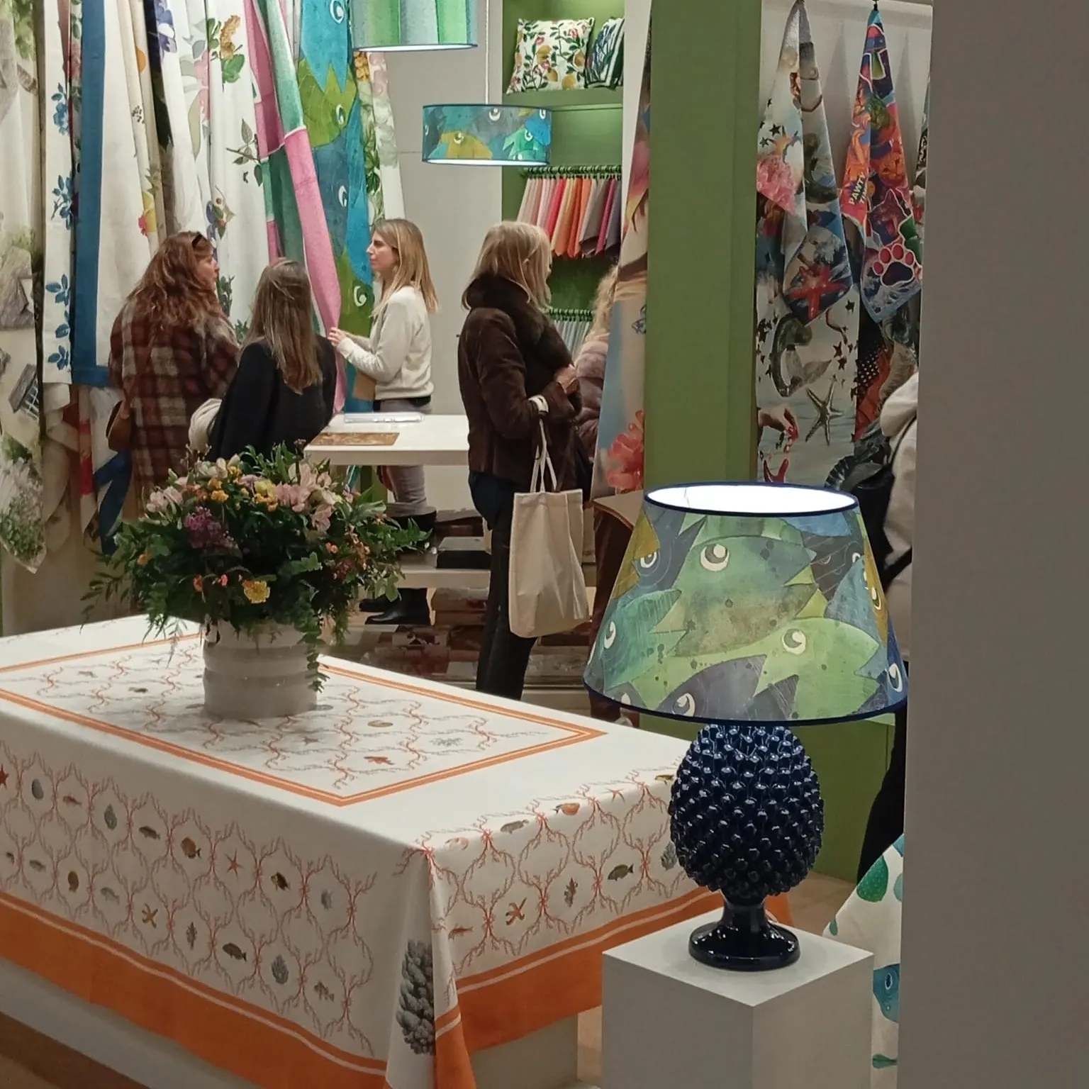 Tavola dello stand con lampada in ceramica blu e tovaglia ricamata