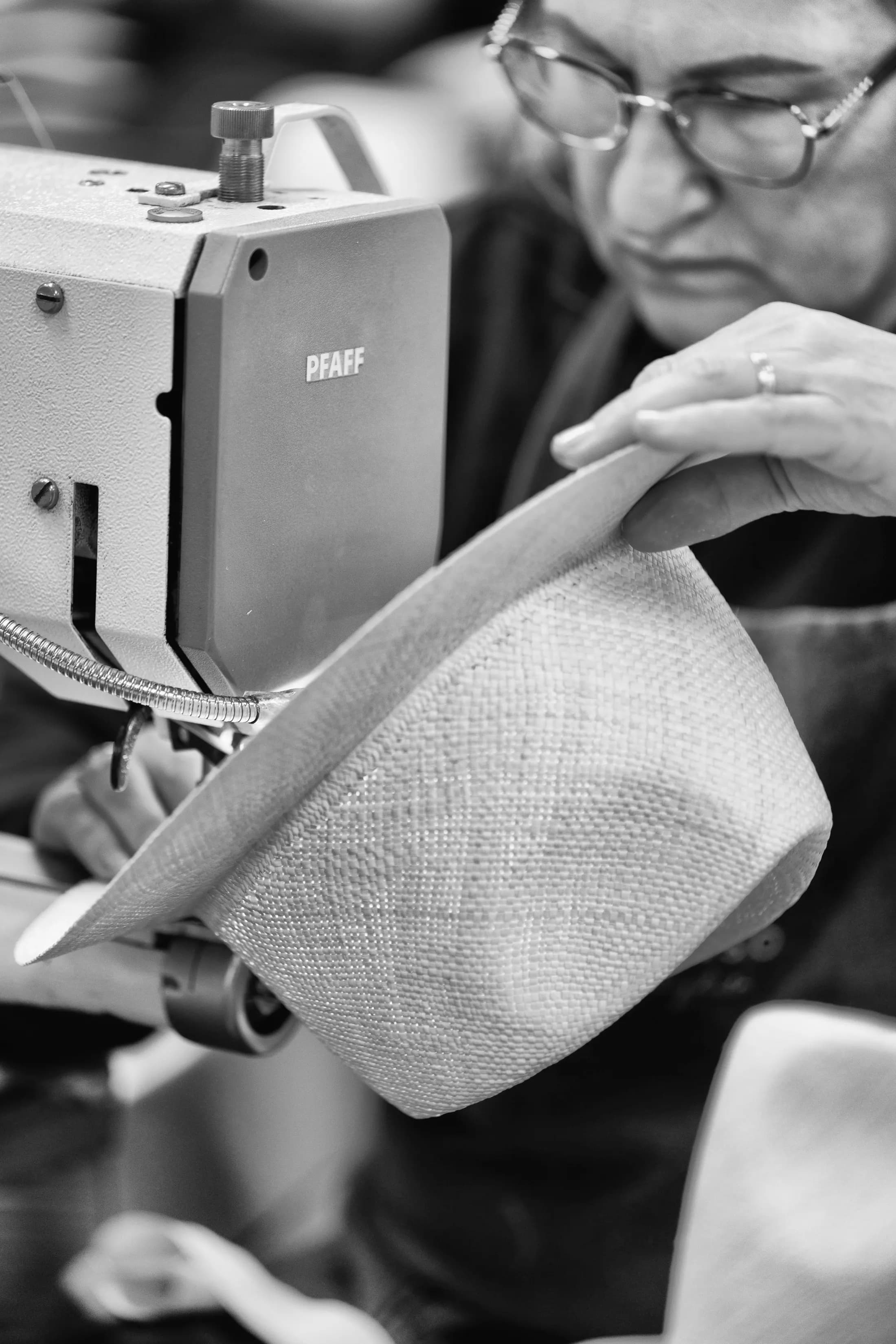 Operaia che guida un cappello sotto la macchina da cucire