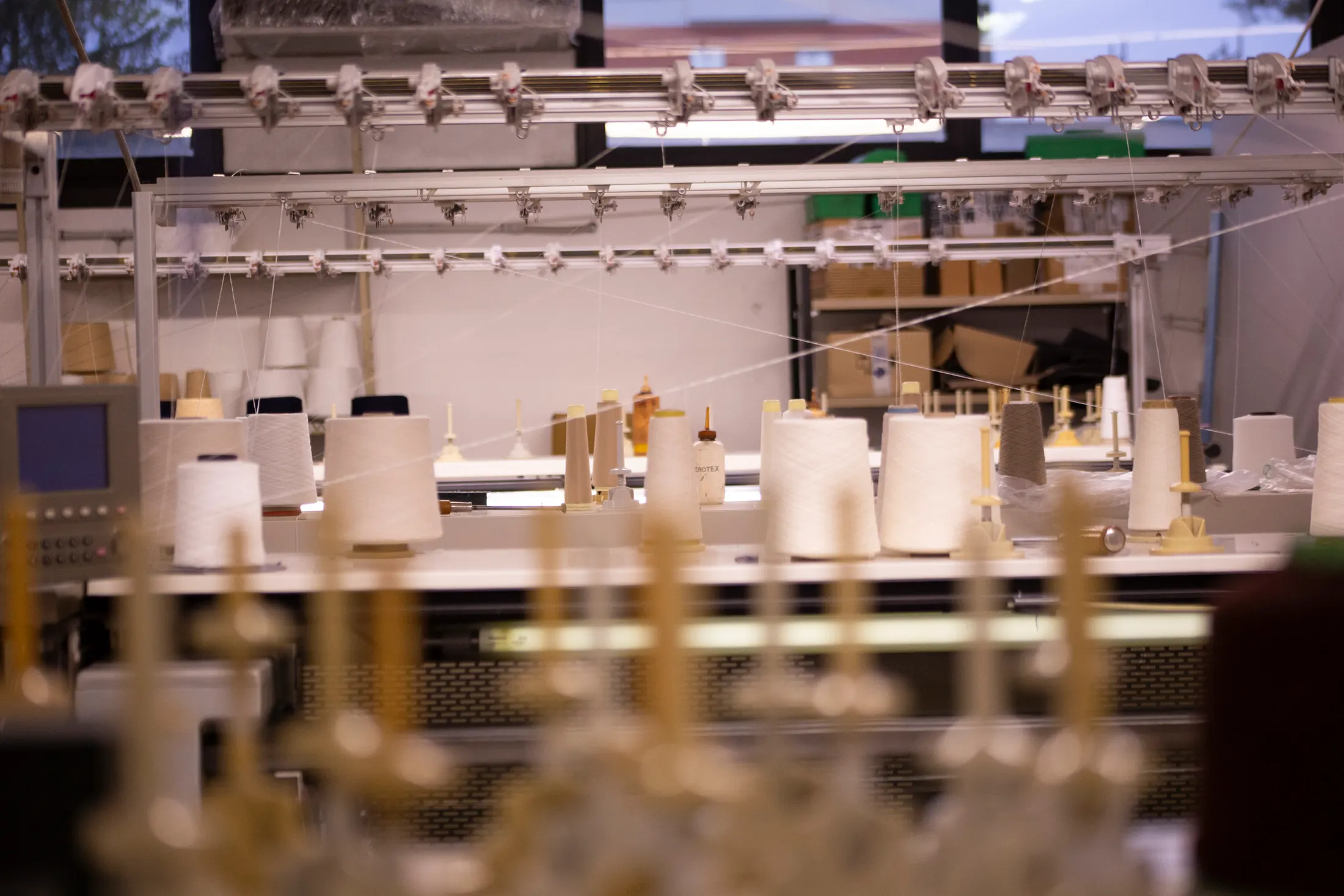 Tecnico al telaio circolare fra i coni di filato, bianco e nero