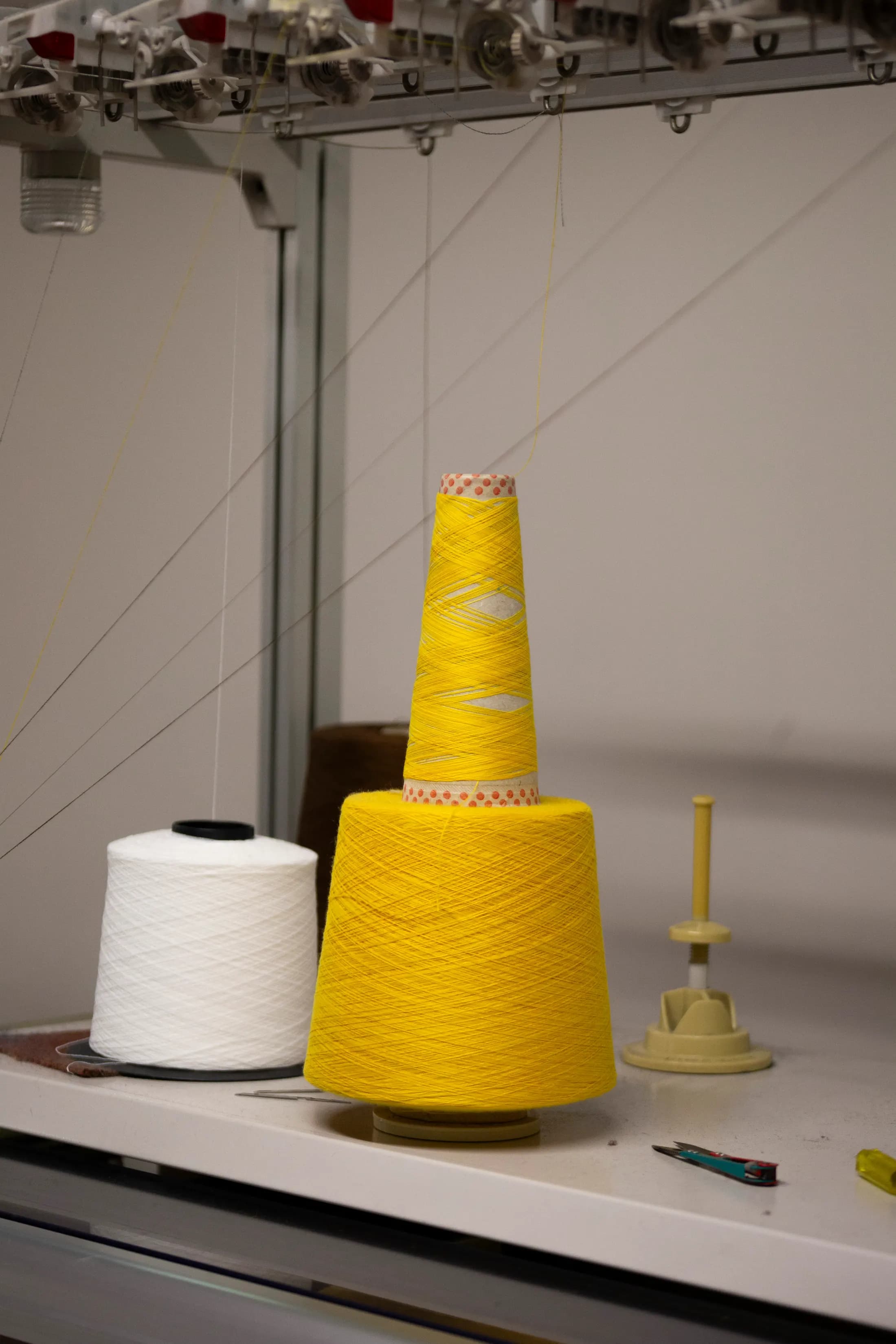 Cono di filato giallo accanto a uno bianco su un banco di lavoro